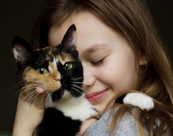 Ein Mädchen kuschelt mit einer Katze, die in die Kamera schaut